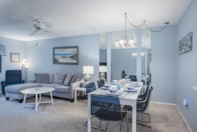 carpeted dining area with a textured ceiling and ceiling fan with notable chandelier