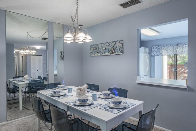 carpeted dining room with a notable chandelier and a textured ceiling