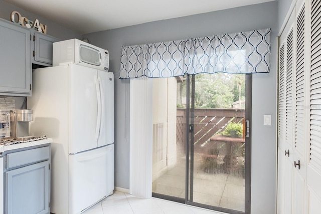 kitchen featuring white appliances, gray cabinets, and light tile patterned floors