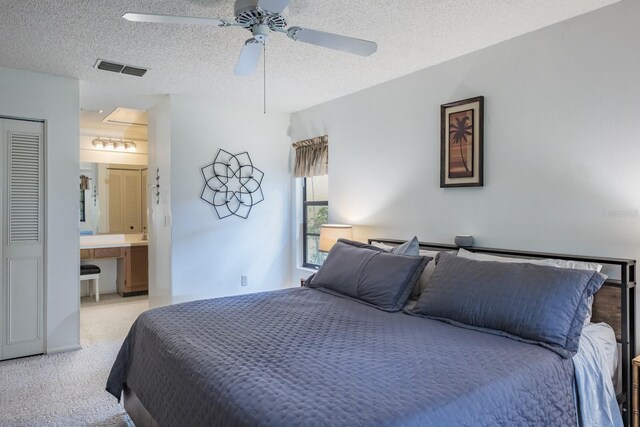 carpeted bedroom with a textured ceiling, connected bathroom, and ceiling fan