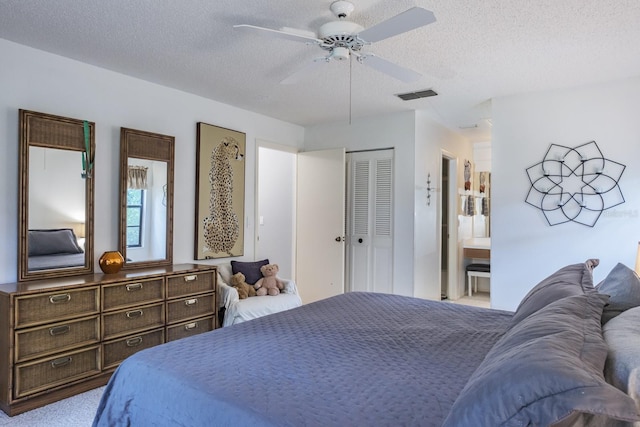 bedroom with a closet, connected bathroom, ceiling fan, carpet, and a textured ceiling