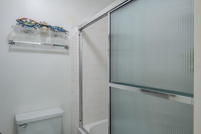 bathroom featuring bath / shower combo with glass door and toilet