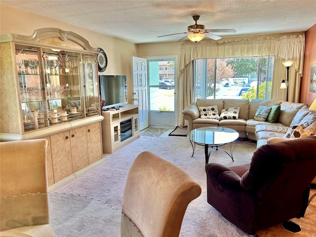 living room featuring ceiling fan, light colored carpet, and a textured ceiling