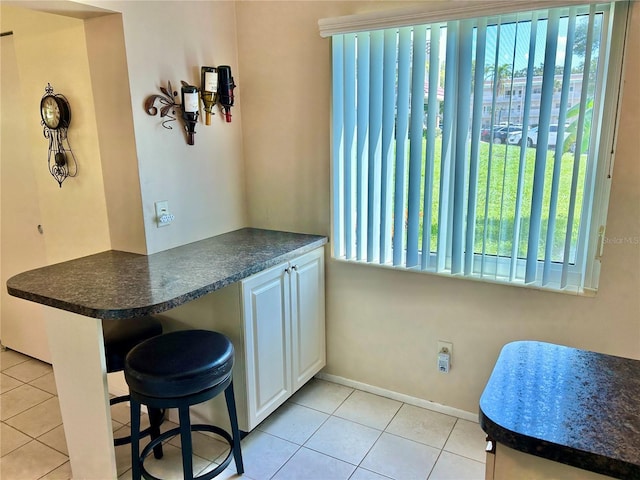 interior space featuring a wealth of natural light, white cabinets, and light tile patterned flooring