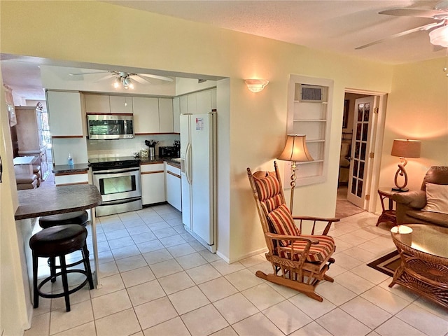 kitchen featuring white cabinets, stainless steel appliances, ceiling fan, and light tile patterned flooring