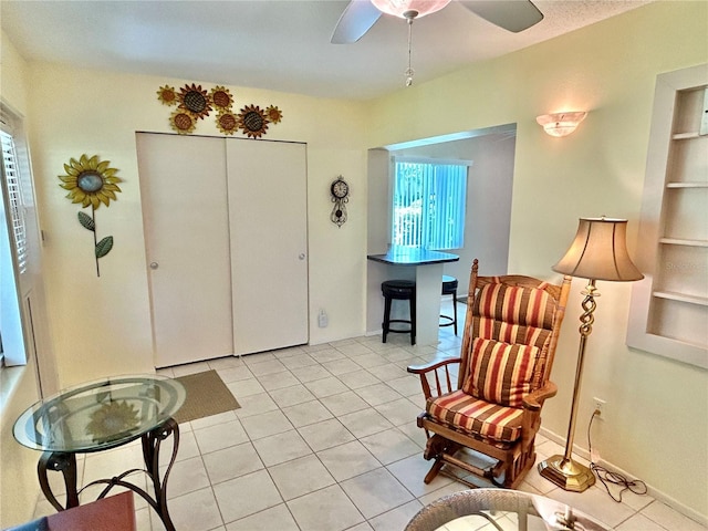 sitting room with built in shelves, ceiling fan, and light tile patterned floors