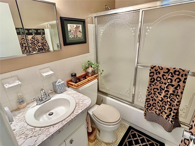 full bathroom featuring toilet, combined bath / shower with glass door, tile walls, vanity, and tile patterned flooring