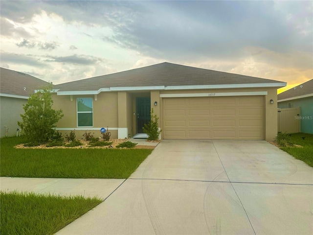 single story home featuring a garage and a lawn