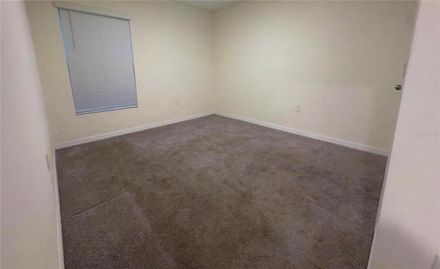 spare room featuring dark carpet