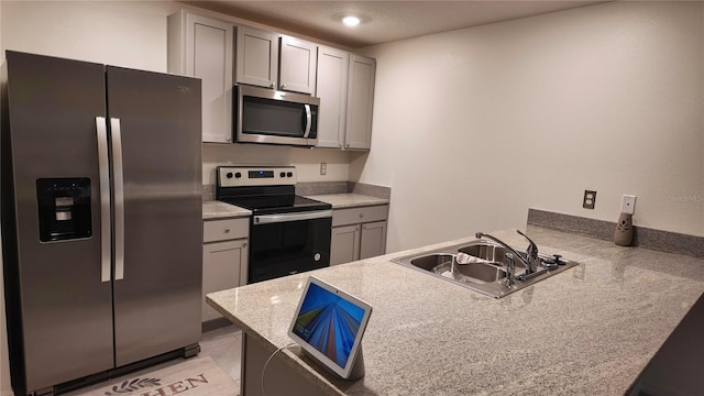 kitchen with stainless steel appliances, sink, gray cabinetry, and kitchen peninsula