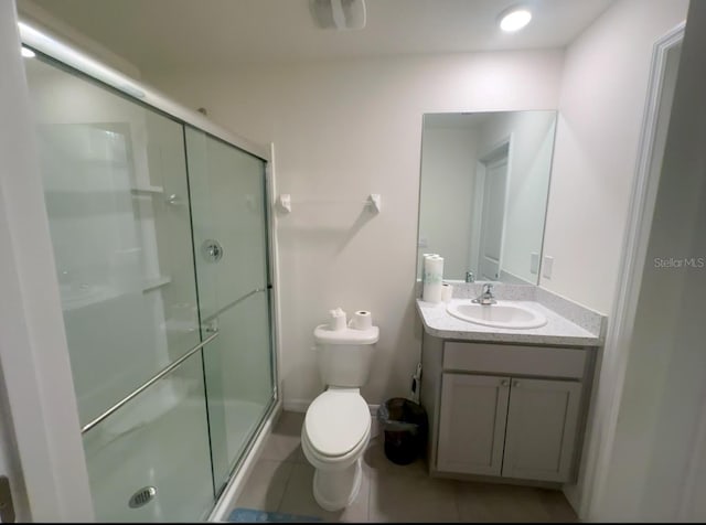 bathroom with an enclosed shower, vanity, tile patterned floors, and toilet