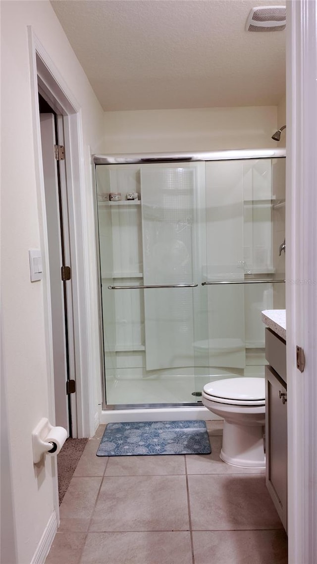 bathroom with vanity, toilet, an enclosed shower, and tile patterned flooring