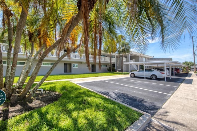 view of parking / parking lot featuring a carport and a yard