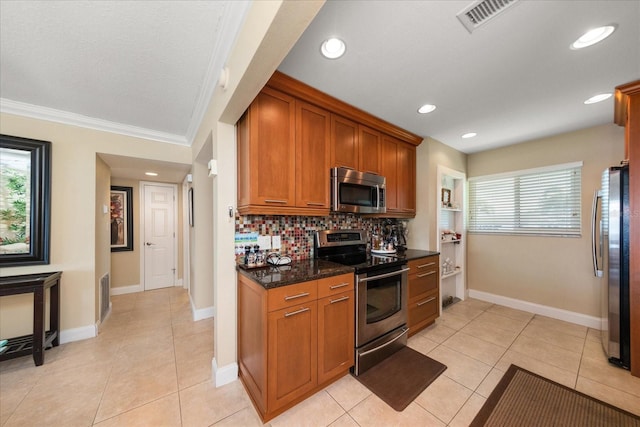 kitchen with crown molding, dark stone counters, light tile patterned floors, stainless steel appliances, and backsplash