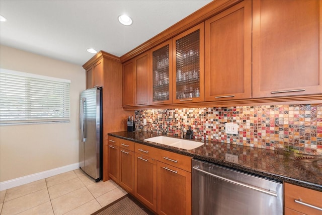 kitchen featuring stainless steel appliances, sink, dark stone countertops, and decorative backsplash