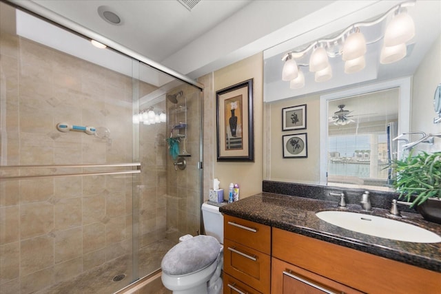 bathroom with a shower with door, vanity, and toilet