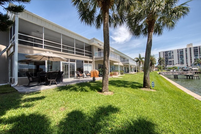 back of house featuring a water view, a sunroom, and a lawn