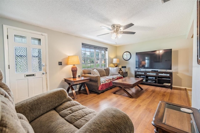 living room featuring light hardwood / wood-style floors, a textured ceiling, and ceiling fan