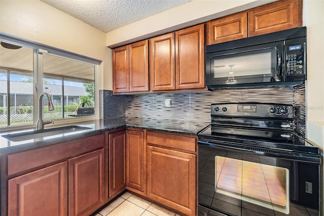 kitchen with dark stone counters, light tile patterned flooring, black appliances, tasteful backsplash, and sink