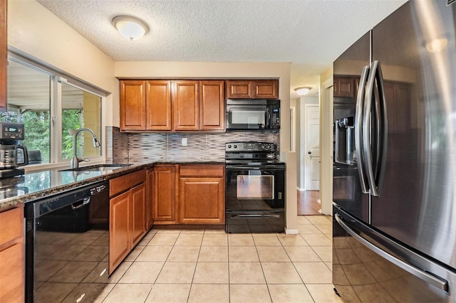 kitchen with black appliances, sink, light tile patterned floors, decorative backsplash, and dark stone countertops