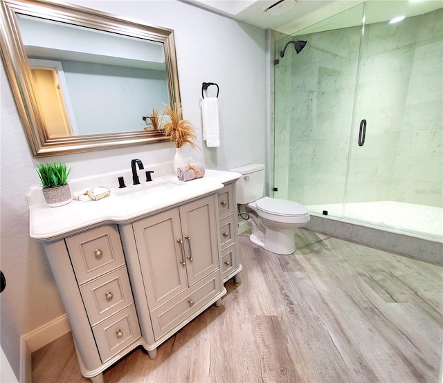 bathroom with hardwood / wood-style flooring, vanity, an enclosed shower, and toilet