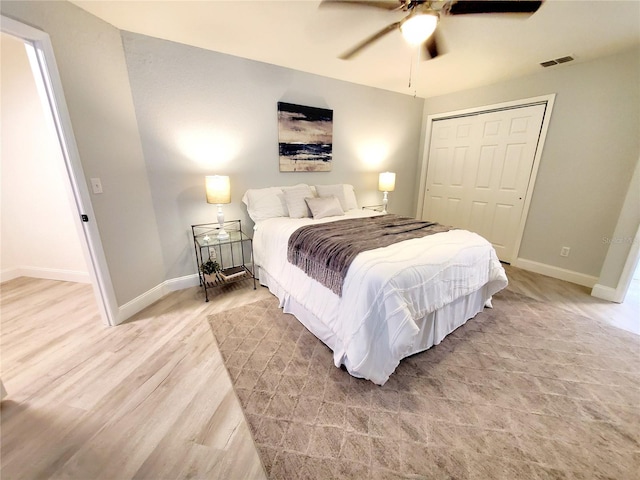 bedroom featuring a closet, visible vents, light wood-style flooring, a ceiling fan, and baseboards