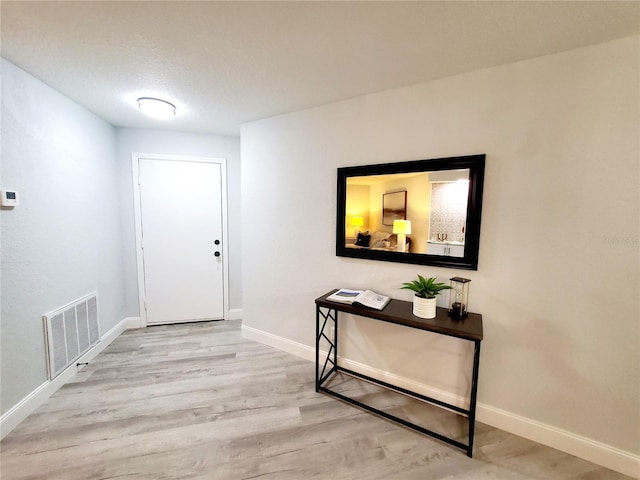 entrance foyer with a textured ceiling, wood finished floors, visible vents, and baseboards