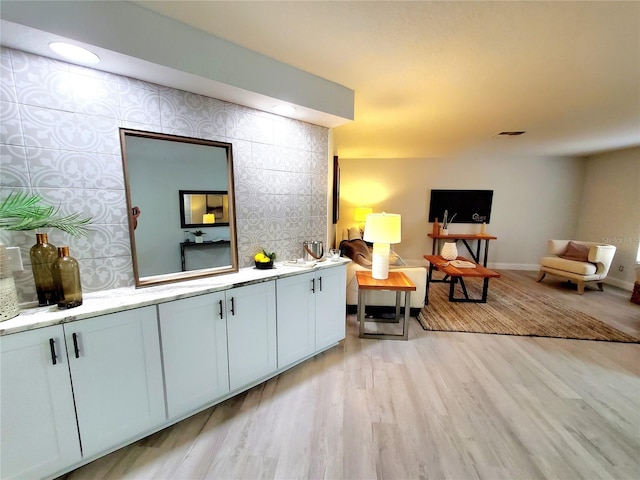 living area featuring light wood-style floors, baseboards, visible vents, and wallpapered walls