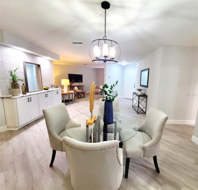 dining area with light wood-style flooring, visible vents, a chandelier, and baseboards