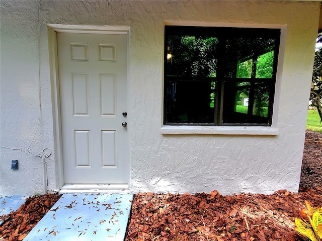 doorway to property featuring stucco siding