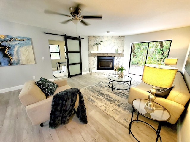 living room featuring a healthy amount of sunlight, a barn door, a fireplace, and wood finished floors