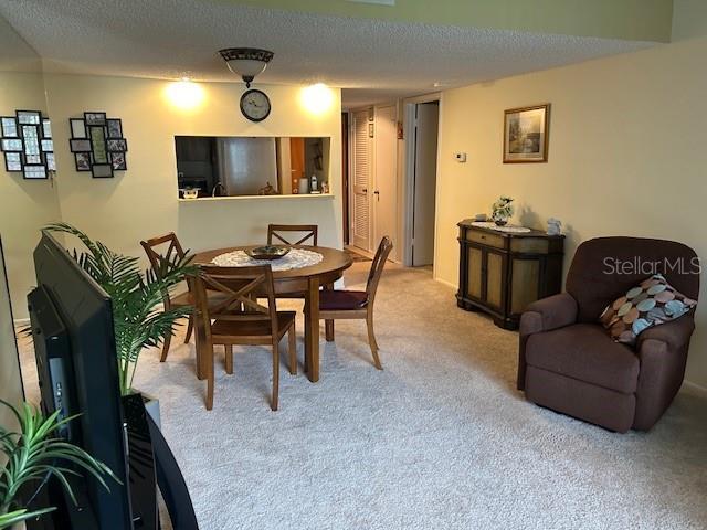 dining area featuring light carpet and a textured ceiling