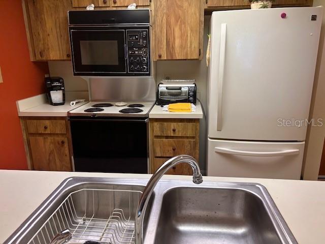 kitchen with sink, white fridge, and electric range