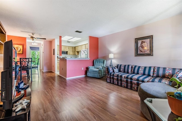 living room featuring ceiling fan, dark hardwood / wood-style floors, and a textured ceiling