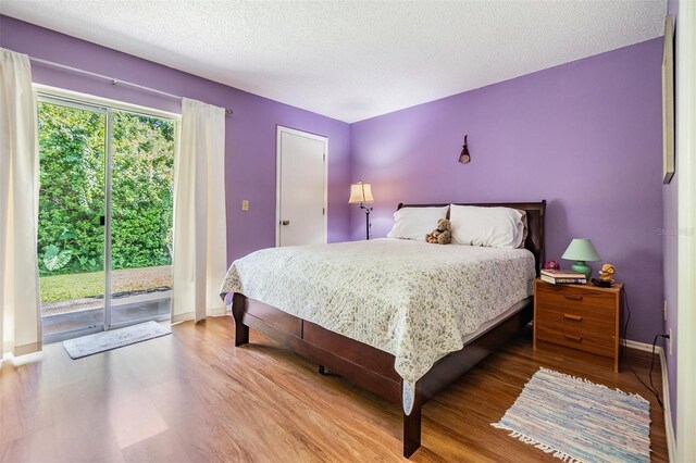 bedroom featuring a textured ceiling, hardwood / wood-style flooring, and access to outside