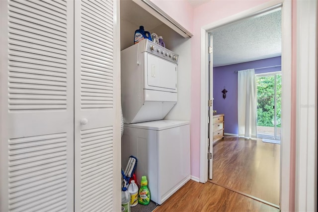 washroom with light wood-type flooring, a textured ceiling, and stacked washer and dryer