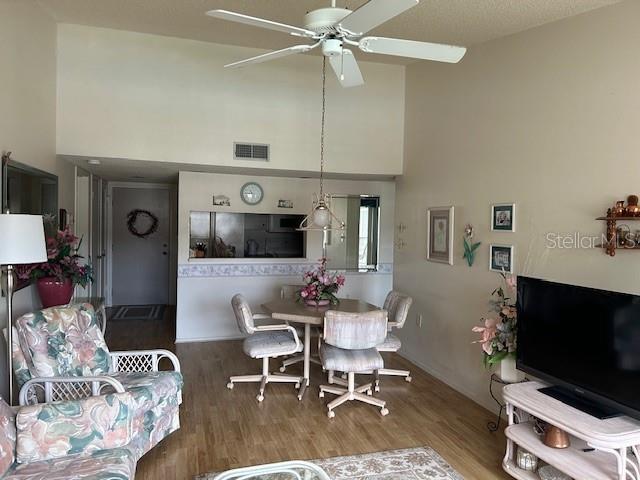 dining area with a high ceiling, wood-type flooring, and ceiling fan