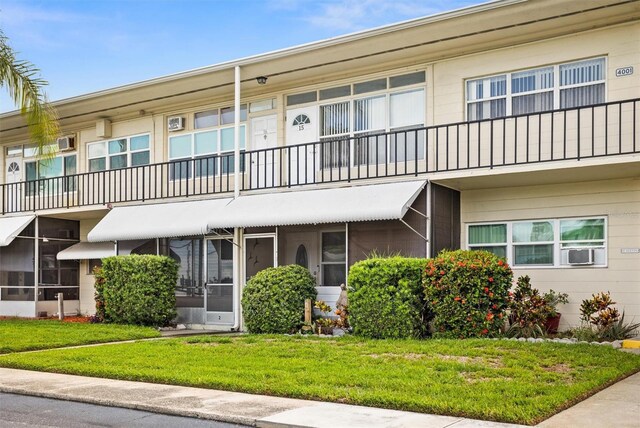 view of front of home featuring a balcony, cooling unit, and a front lawn