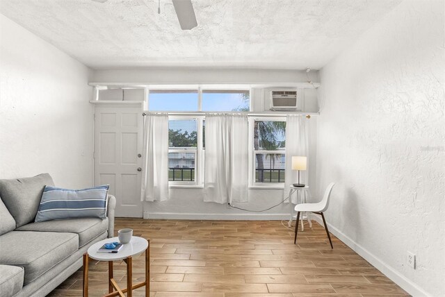 living room with light hardwood / wood-style floors, an AC wall unit, and a textured ceiling