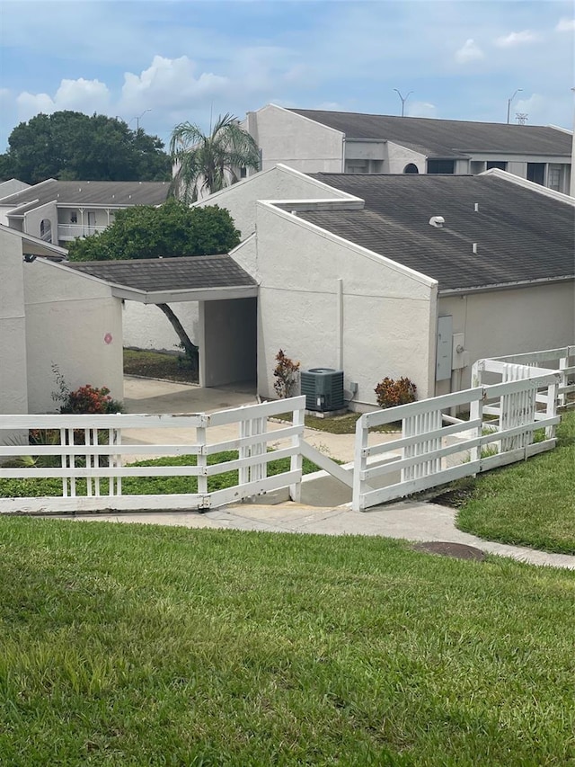 view of side of property featuring central AC unit and a lawn