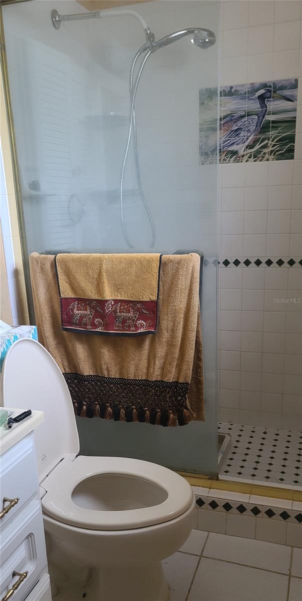 bathroom with tile patterned floors, toilet, a shower with door, and vanity