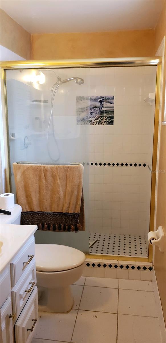 bathroom with a shower with shower door, toilet, tile patterned flooring, and vanity