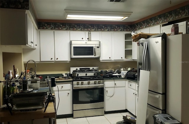 kitchen with white cabinetry, stainless steel appliances, and light tile patterned flooring