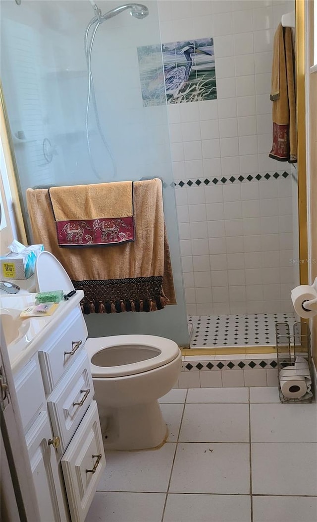 bathroom with tile patterned flooring, toilet, a tile shower, and vanity