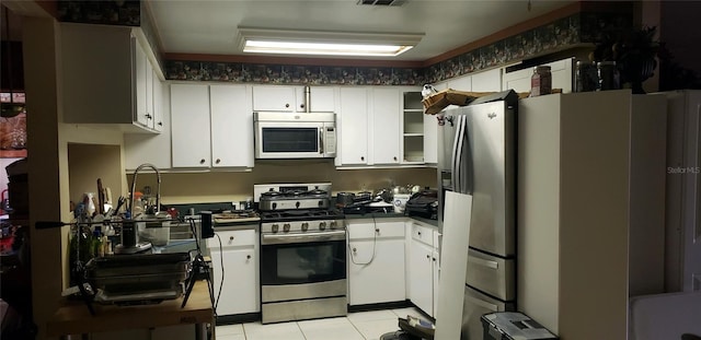 kitchen with white cabinets, light tile patterned flooring, and stainless steel appliances