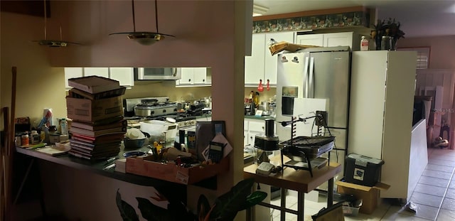 kitchen with appliances with stainless steel finishes, light tile patterned flooring, and white cabinets