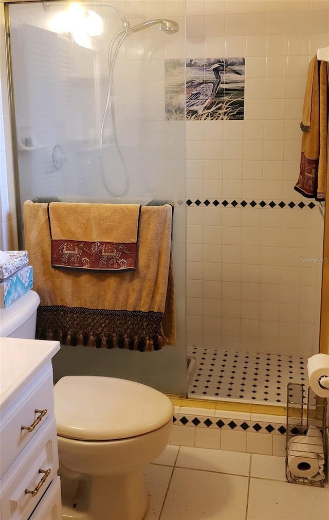 bathroom featuring tile patterned flooring, toilet, tiled shower, and vanity