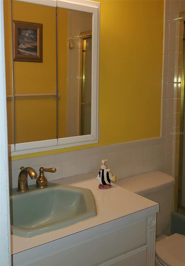 bathroom with decorative backsplash, vanity, and toilet