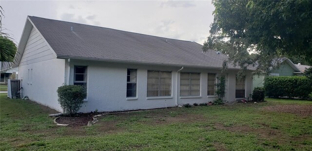 back of house with cooling unit and a lawn