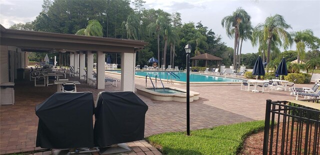 view of swimming pool with a patio, grilling area, and a community hot tub